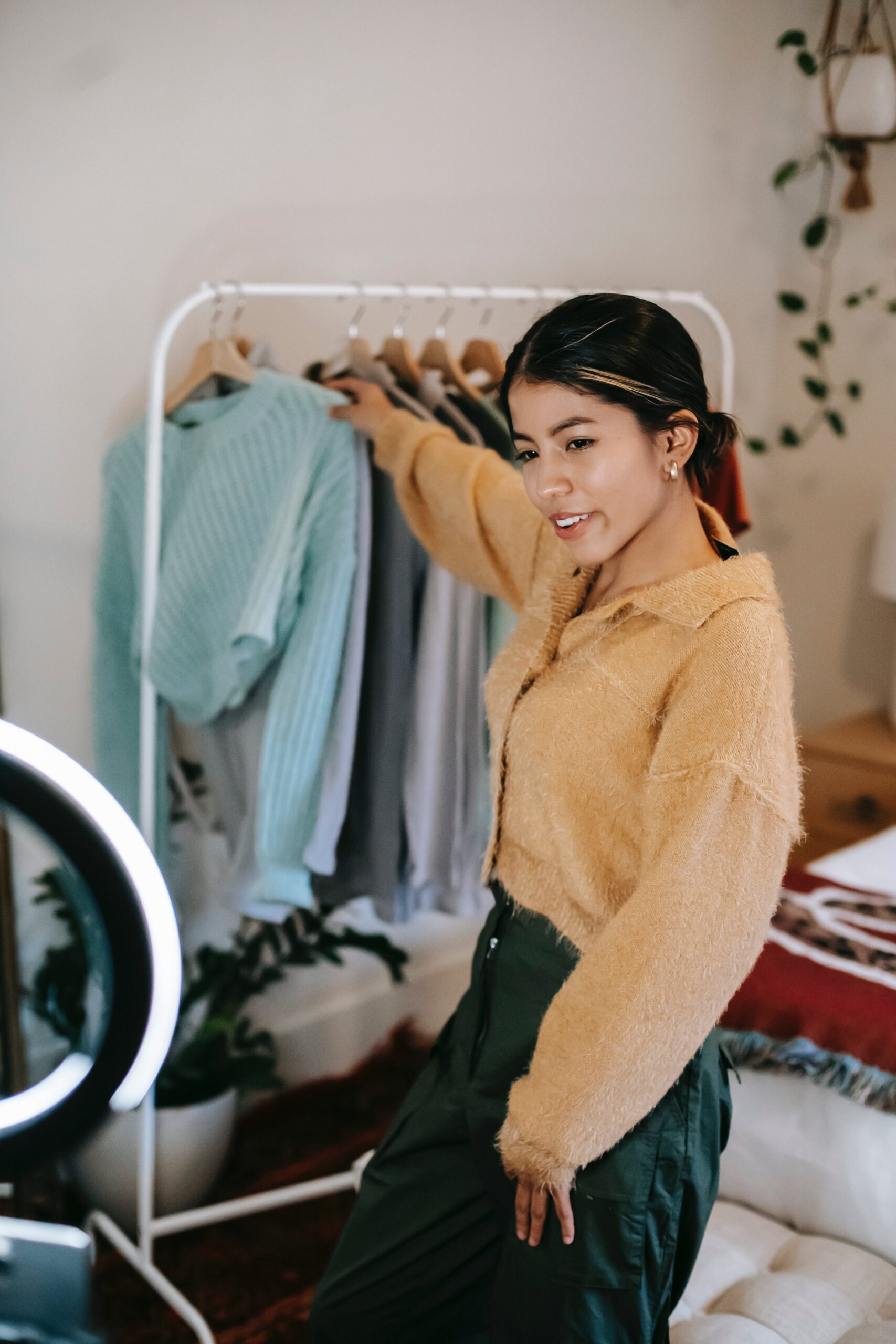 pexels-photo-6347557 Trendy smiling woman taking clothes from rail while shooting video